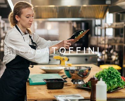Chef preparando pratos em cozinha profissional com o logotipo Casa Toffini